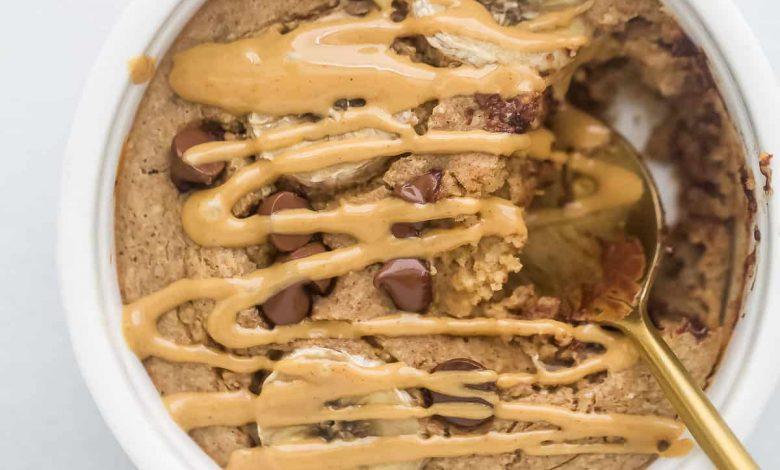 Warm baked oatmeal inside of a ramekin with a drizzle of melty peanut butter on top